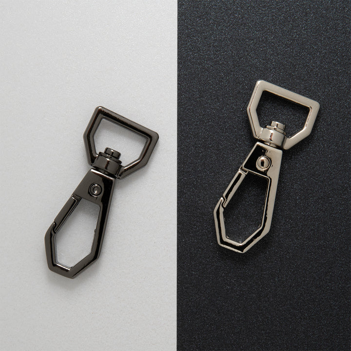 Gun metal and nickel coloured dog clip on a two tone background
